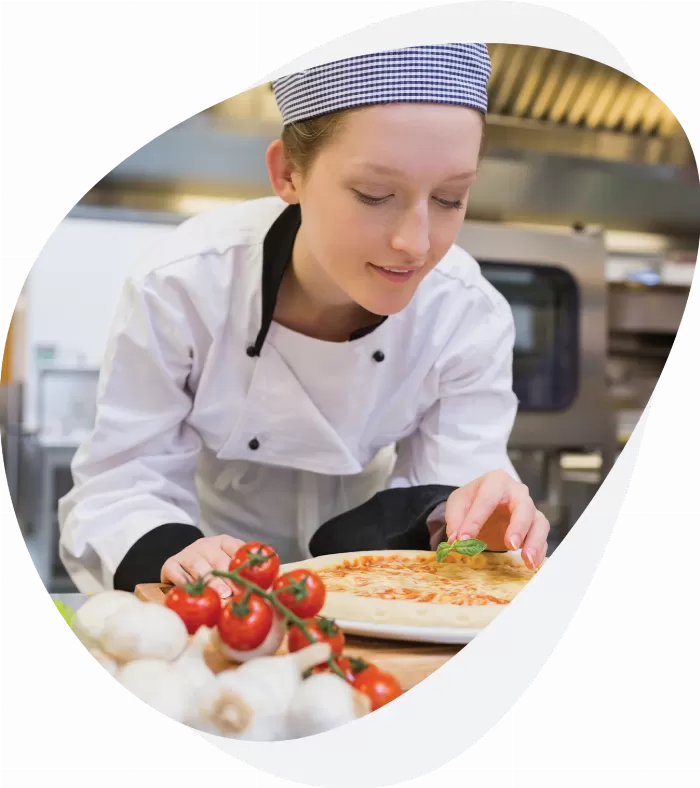 A young girl cooking a pizza on a Busy Bees Education and Training production chef level 2 apprenticeship.