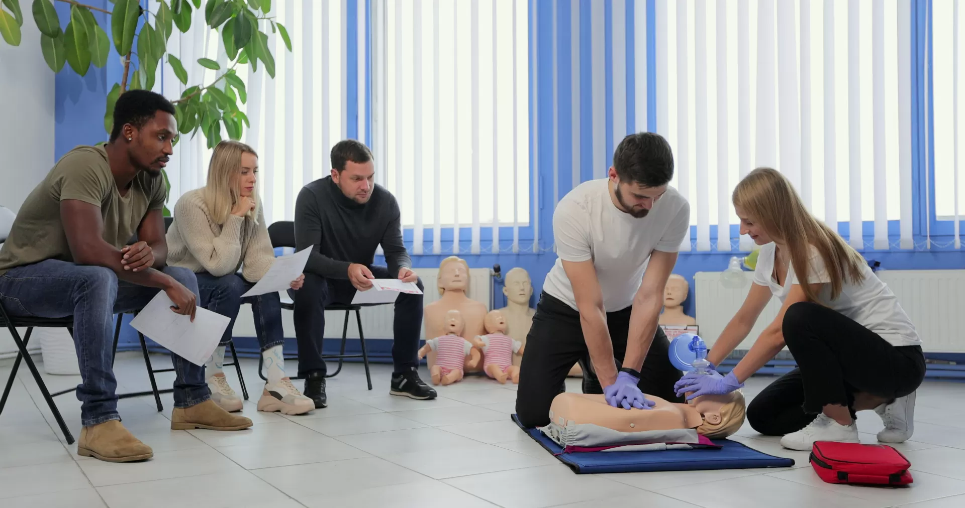 A man and woman demonstrating how to do CPR to others.