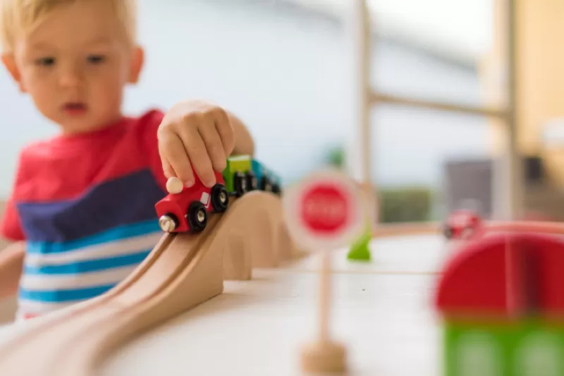 A child playing with a wooden train set