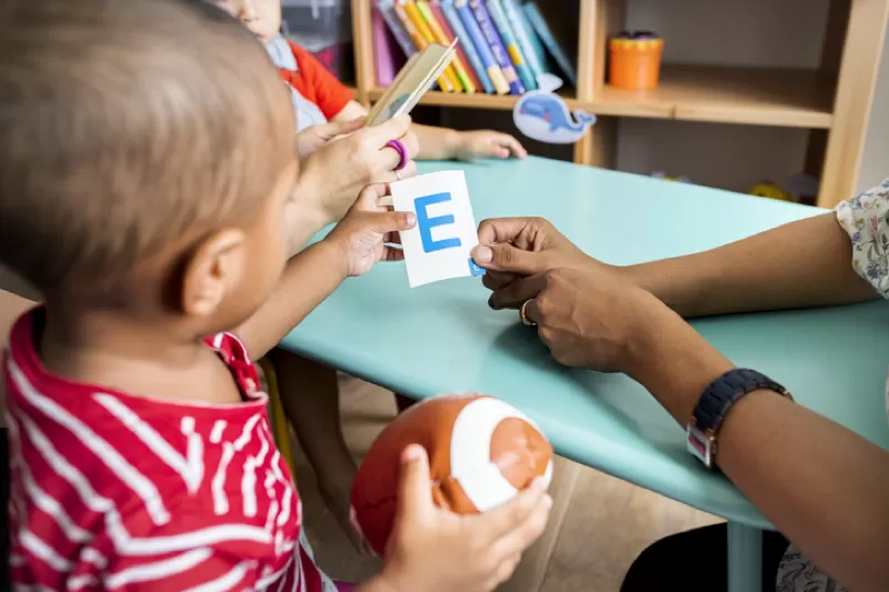 A child learning the letter E with a flash card