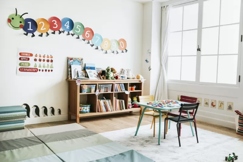 A child's classroom with a caterpillar number wall and a bookshelf