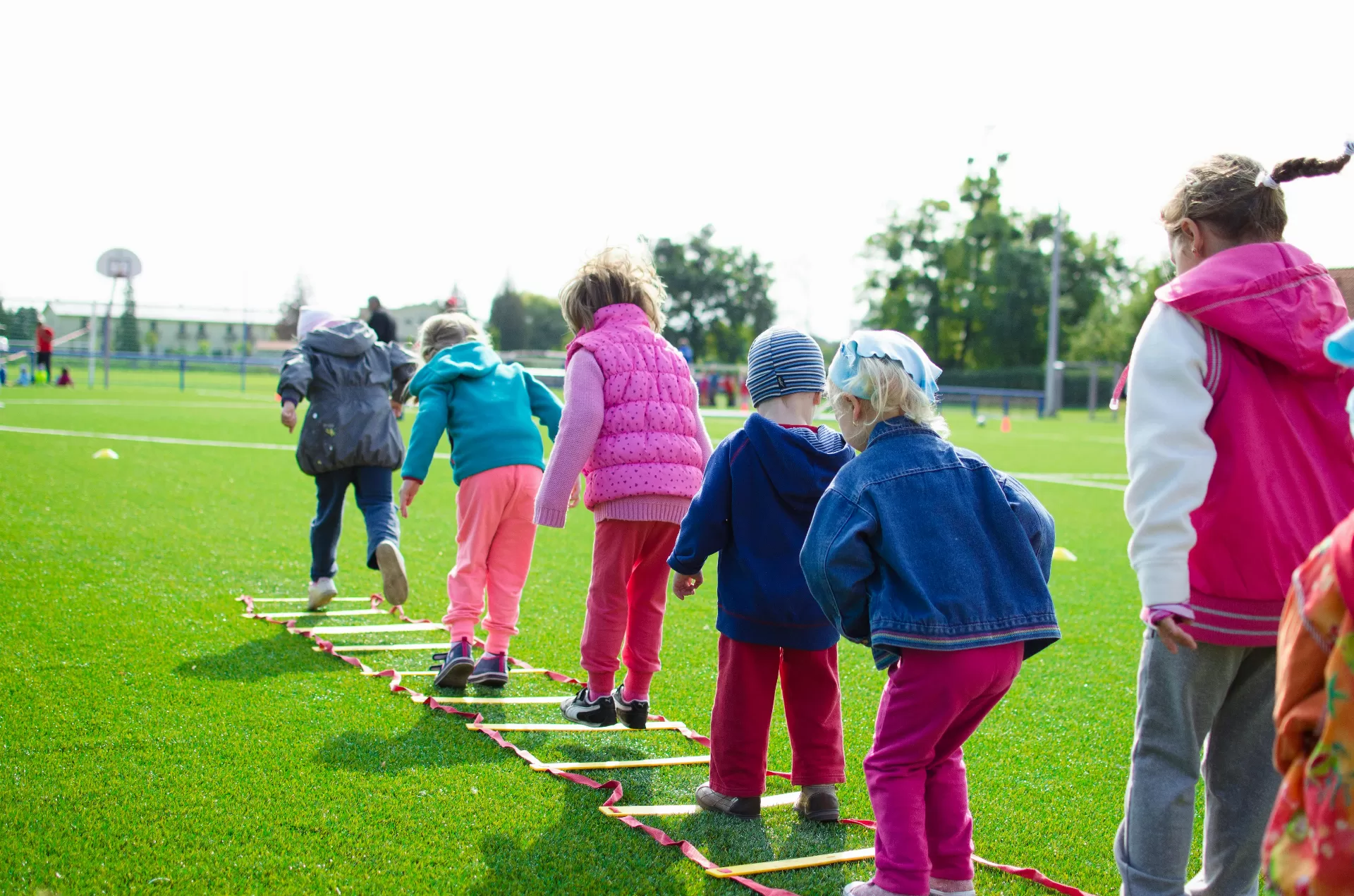 A line of children playing on a ladder on the grass